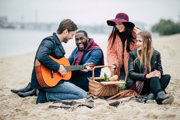Happy friends with guitar at picnic - 写真・画像