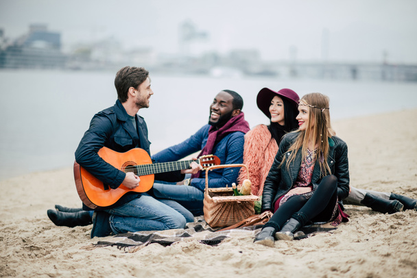 Gelukkige vrienden met gitaar op picnic - Foto, afbeelding