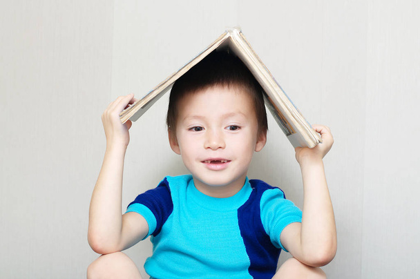 Happy boy with book on head making roof - Φωτογραφία, εικόνα