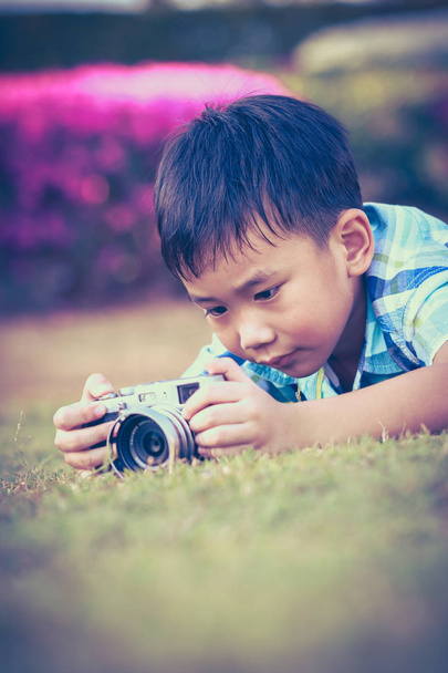 Мальчик фотографирует на камеру, исследует природу в парке
.  - Фото, изображение