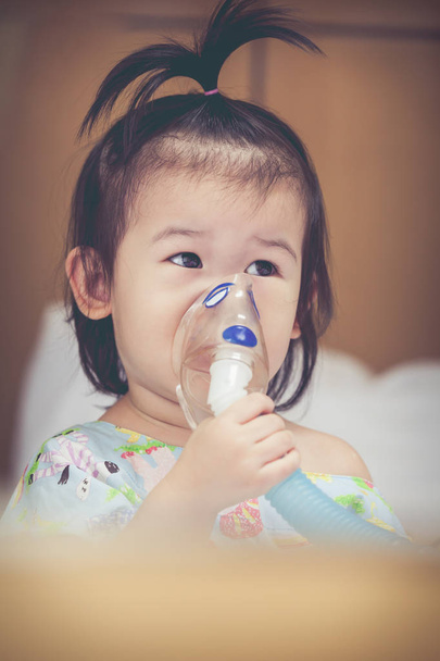Азиатский ребенок держит ингалятор пара маски для лечения астмы
.  - Фото, изображение