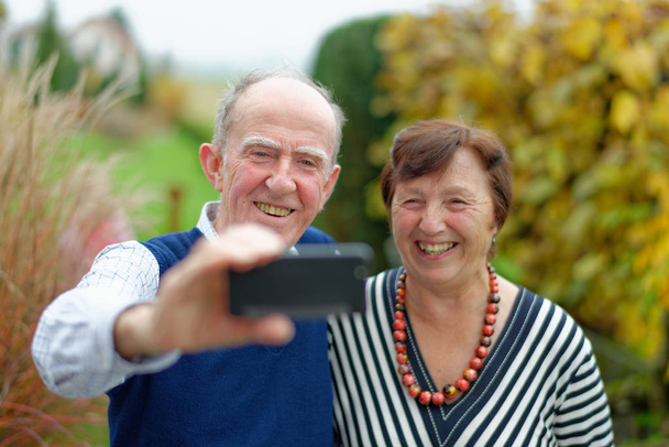  Happy senior couple bonding to each other and making selfie - Photo, Image