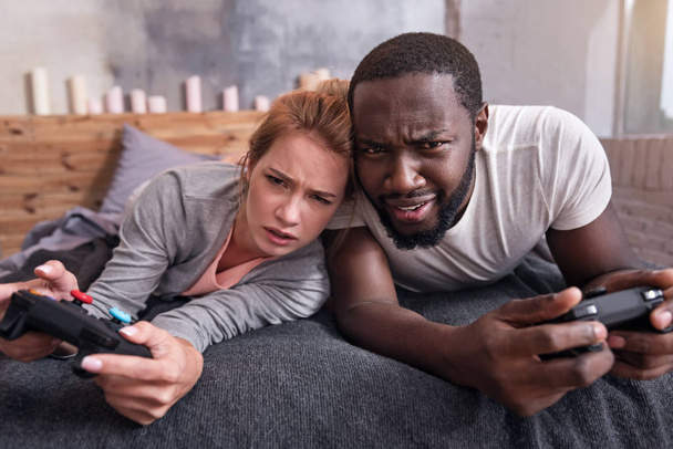 Amused couple playing video games in bedroom together - Fotó, kép