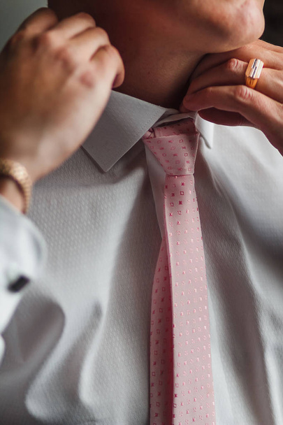 Крупним планом корпоративний чоловік коригує свою модну рожеву краватку
 - Фото, зображення