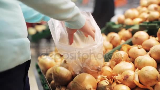 mujer poniendo cebolla a la bolsa en la tienda de comestibles
 - Metraje, vídeo