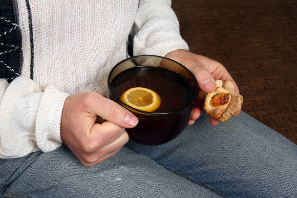 mãos de um homem com uma xícara de chá e biscoitos
 - Foto, Imagem
