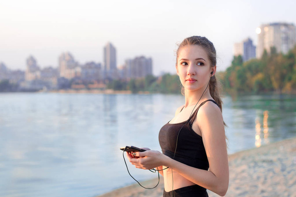 Fitness meisje aan meer luisteren naar muziek op mobiele telefoon - Foto, afbeelding