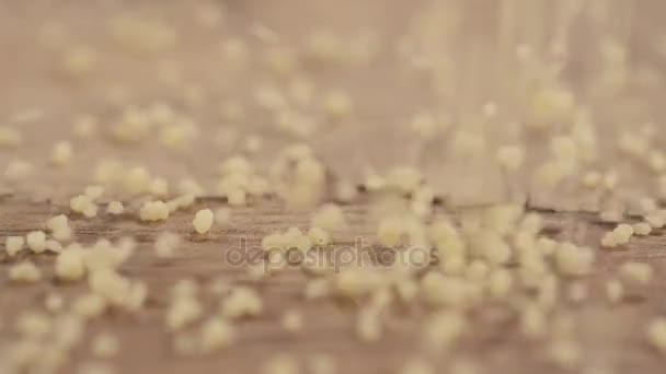 Millet porridge falling on a wooden cutting board  - Filmati, video