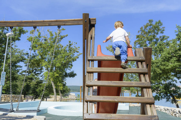 Little boy climbing ladder on slide - Fotó, kép
