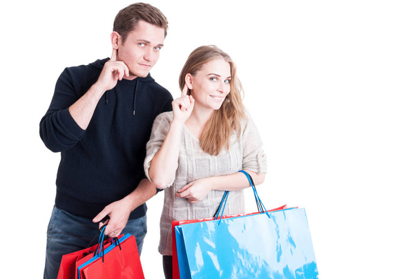Couple holding shopping bags making can't hear gesture - 写真・画像