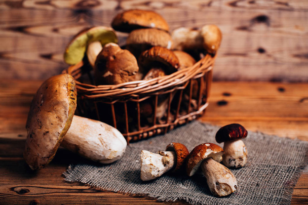 Boletus mushrooms in a basket on a wooden board - Foto, afbeelding