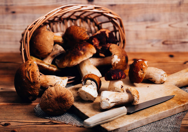Boletus mushrooms in a basket on a wooden board - Foto, Imagen