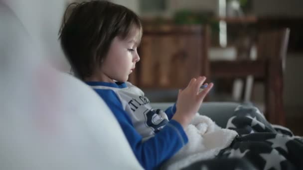 Little preschool child, boy, playing on mobile phone on the sofa at night - Filmagem, Vídeo