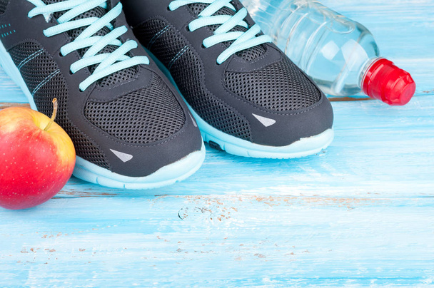 Sport equipment and sneakers. Sport shoes, apple, bottle of water. Concept healthy lifestyle, healthy food, sport and diet - Photo, Image