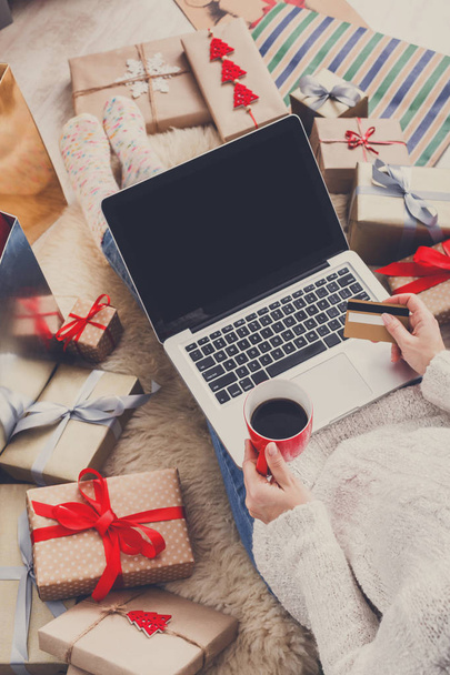 Γυναίκα κάνει χριστουγεννιάτικα ψώνια σε απευθείας σύνδεση με το laptop, πάνω από την προβολή - Φωτογραφία, εικόνα