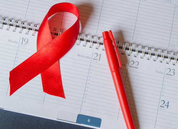 Red ribbon on the calendar to raise awareness against AIDS copy space - Foto, afbeelding
