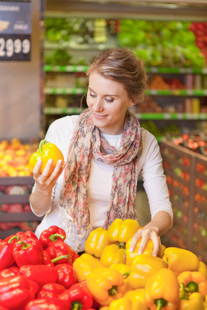 Retrato de una hermosa mujer joven eligiendo verduras en la tienda de comestibles
 - Foto, Imagen