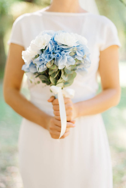 Bride in simple white dress holds bouquet of hydrangea - Foto, immagini