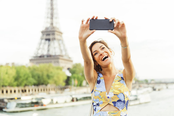Woman doing a selfie in Paris with Eiffel tower in background - 写真・画像