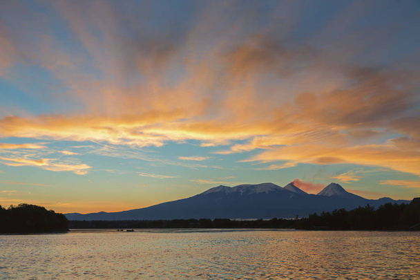 Kaunis auringonnousu tulivuorten yli Kluchevskaja ryhmä heijastus joessa Kamchatka
. - Valokuva, kuva