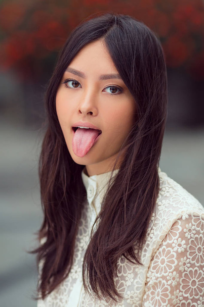 Beautiful asian woman showing tongue - Photo, image