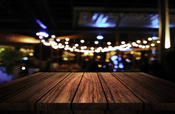 wooden table in front of abstract blurred background of resturant lights  - Foto, Imagem