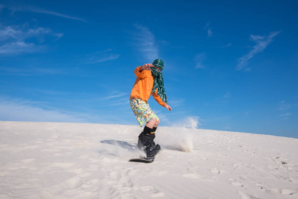 Snowboarder, wearing a scarf riding in desert. Wide angle - Fotoğraf, Görsel
