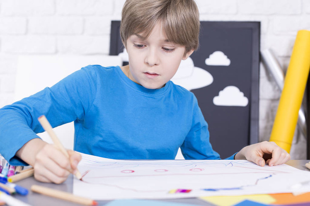 Boy drawing something on a piece of paper - Zdjęcie, obraz