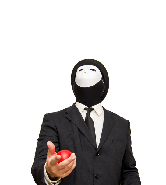 Zakenman met een wit masker en een hoed jongleren met rode ballen - Foto, afbeelding