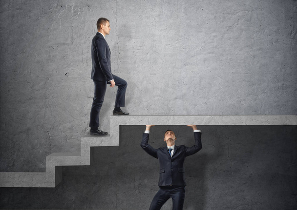 Businessman climbs the concrete stairs, which the other person keeps. - Foto, afbeelding