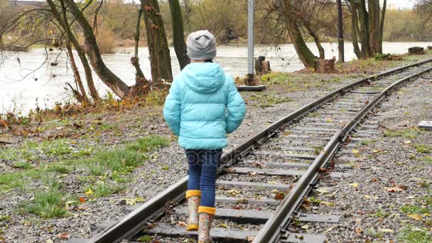 Meisje lopen op railroad tracks. Achteraanzicht van een meisje op de rails. - Video