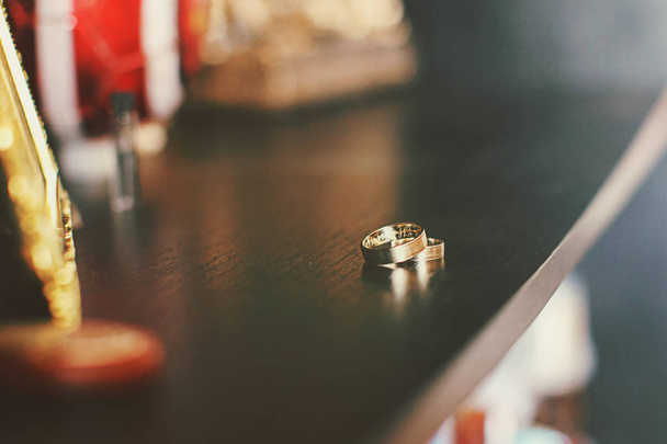 Wedding rings lie and sparkle on a dressing table  - Fotoğraf, Görsel