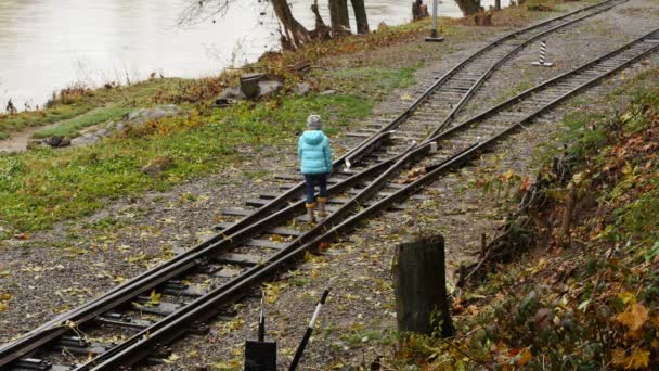 Lány séta a síneken. A lány a válaszúthoz érkezett. A gyermek úgy dönt, hogy az út. - Felvétel, videó