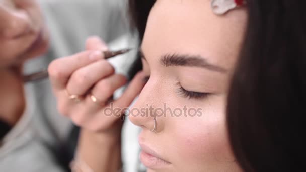 Make up artist paints eyebrows by pencil, Make up artist does make up for model, woman in beauty salon, photo model gets ready for photoshoot - Footage, Video