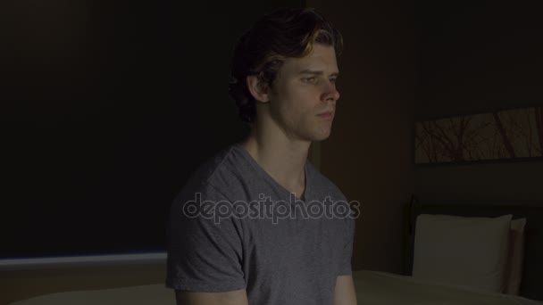 Ülő depressziós fiatal férfi a hálószobában - Felvétel, videó