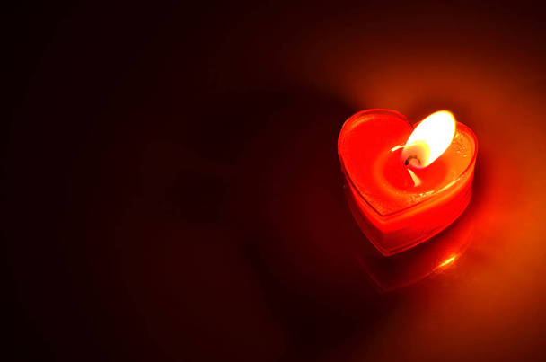 Закрыть горящее сердце красной свечи на темном фоне
 - Фото, изображение