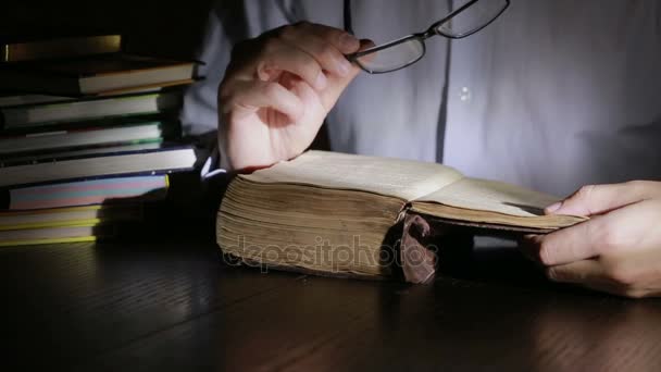 Un hombre inteligente que estudia hasta tarde en la noche, está sentado en el escritorio y leyendo un libro
 - Imágenes, Vídeo