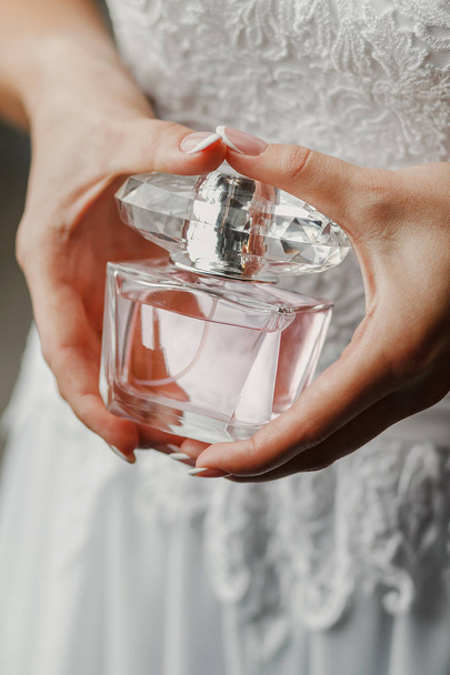 Elegant bride holding in hands a bottle of luxury perfume - Fotoğraf, Görsel