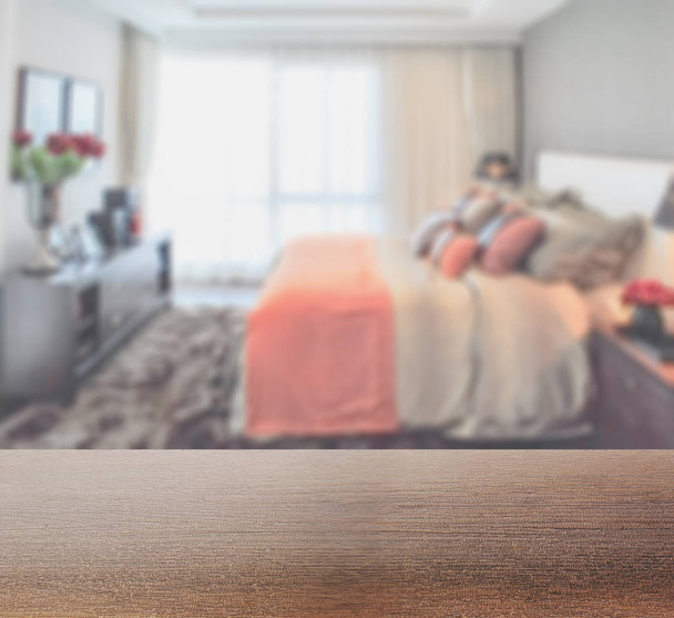 wooden table top with blur of bedroom in modern interior style - Foto, Imagen