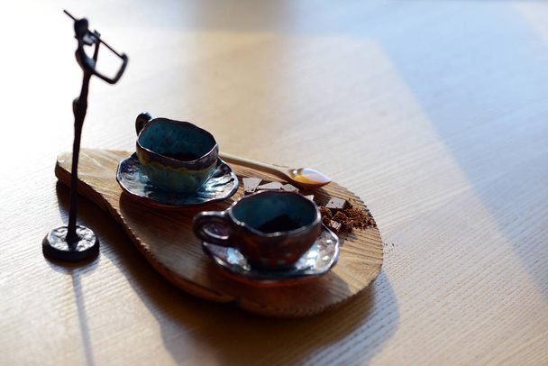 Фигура скрипача стоит рядом с деревянным стендом, на котором стоит чашка кофе и шоколад
. - Фото, изображение