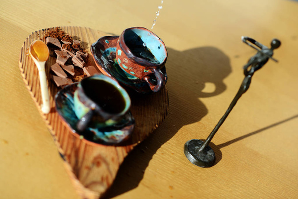 Statuetta violinista in piedi accanto a uno stand di legno su cui poggiano una tazza di caffè e cioccolato
. - Foto, immagini