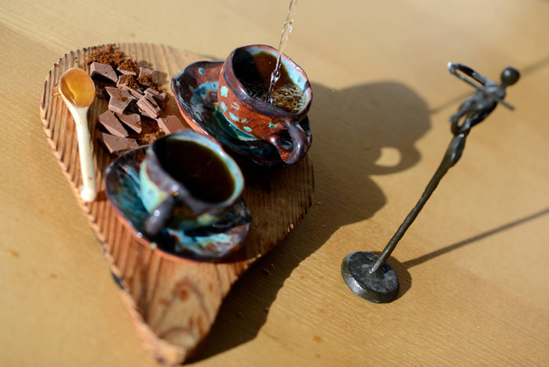 Geigerfigur neben einem Holzständer, auf dem eine Tasse Kaffee und Schokolade stehen. - Foto, Bild