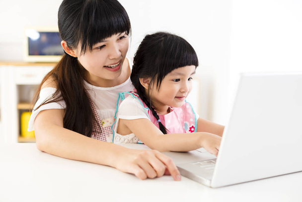 mother with little girl using laptop in the kitchen - Foto, Imagen