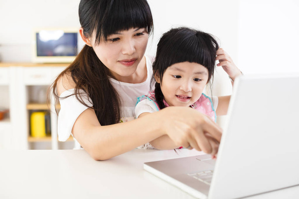 mother with little girl using laptop in the kitchen - Foto, imagen