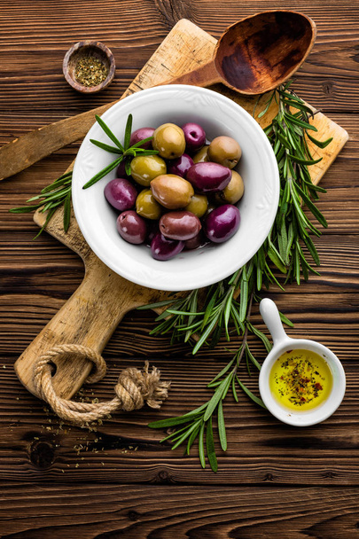 rosemary, olives, olive oil on wooden background - Фото, изображение