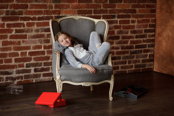 Lovely little girl reclines in a chair with a smile upon the face. - Foto, Bild
