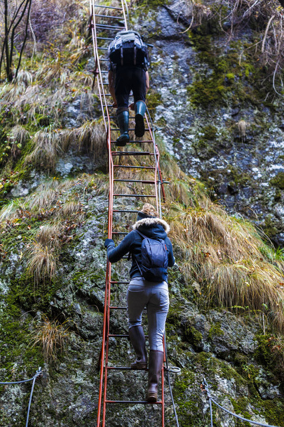 un par de excursionistas trepando por cables de seguridad en un desfiladero
  - Foto, Imagen