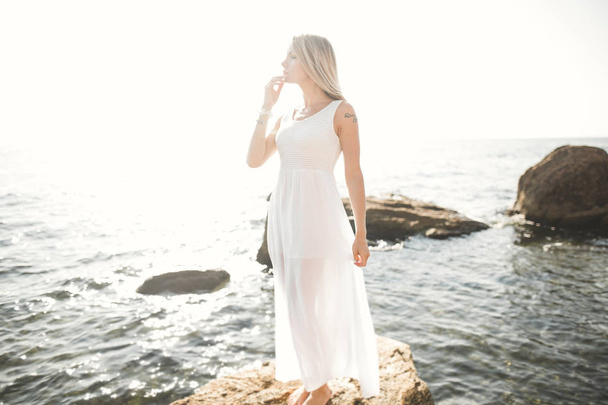портрет молодой женщины, позирующей у моря, одетой в платье
 - Фото, изображение
