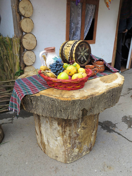 tavolo fatto di tronchi con cesto di frutta e botte di vino
 - Foto, immagini
