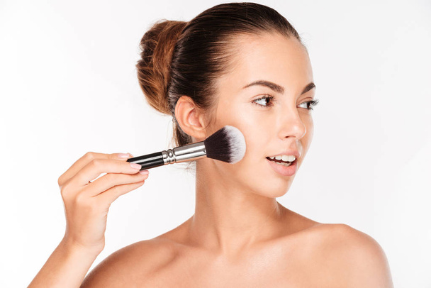 Portrait of beautiful woman applying cosmetic with brush - Foto, Bild